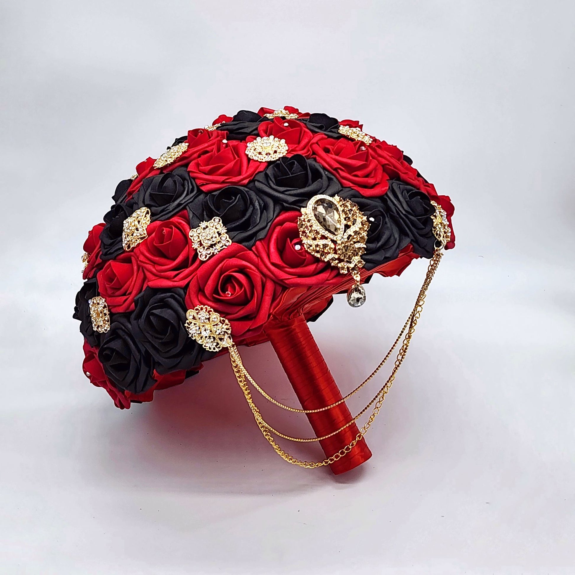 red and black bridal bouquet with cascading gold chains.  made with real touch roses. Handle is made up of satin red ribbon.