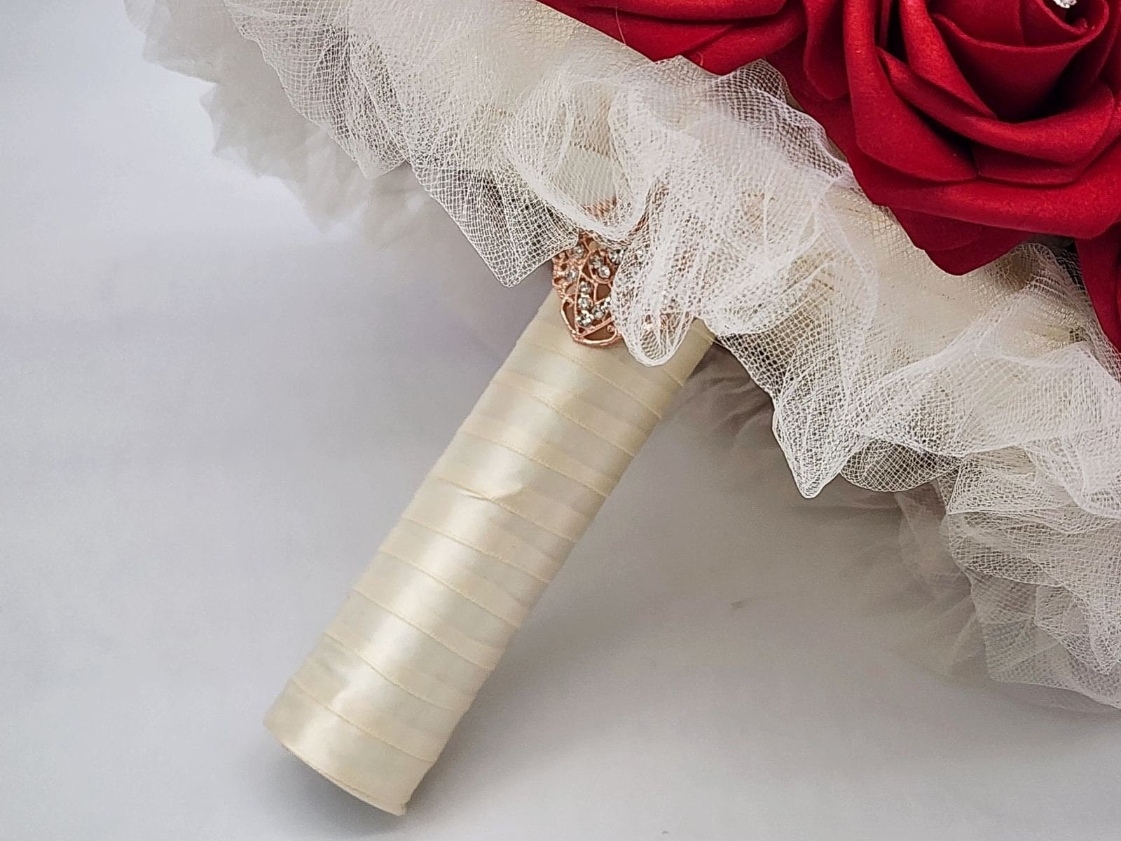 Handle of the bouquet. Ivory tulle, Ivory ribbon, and finished with a gold brooch. 