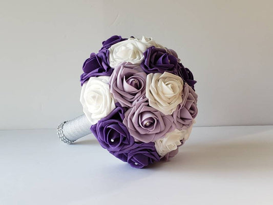 Lilac, Purple, and White Wedding Bouquet made with Real touch roses. Rhinestones are placed in the center of every rose. Handle is made out of silver ribbon and finished with silver bling wrap. 