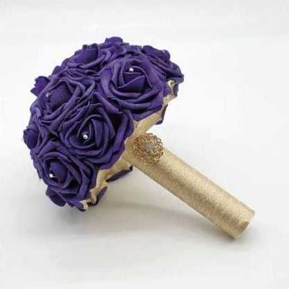 Purple and Gold Bridal Bouquet made with Real touch roses. Rhinestones are scattered on every rose. Handle is made up of gold ribbon and finished with a gold brooch. 