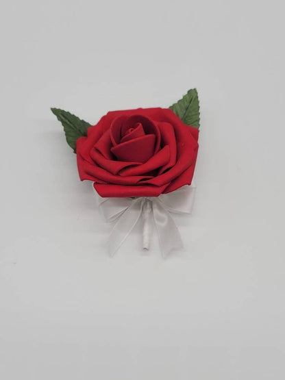 Red rose boutonniere with white satin ribbon. Pearl pin and faux leaves