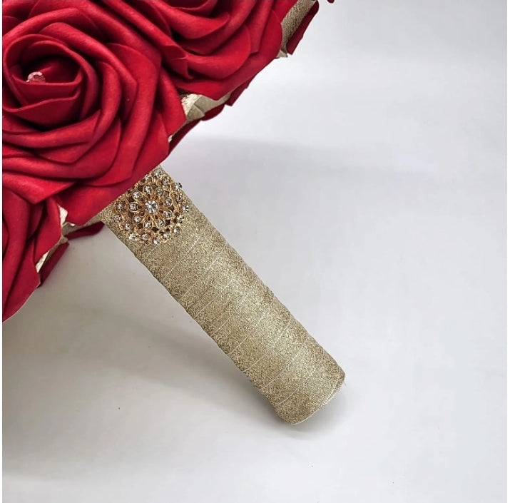 Handle of bouquet made up of gold ribbon and finished with a gold brooch. 