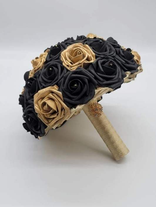 Black and gold bridal bouquet with gold ribbon with gold brooch on handle. Rhinestones on every rose