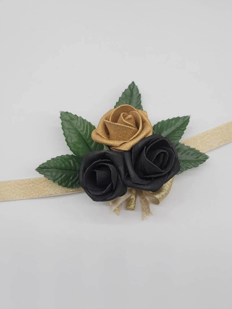 gold and black wrist  corsage with gold ribbon. 5 rose leaves