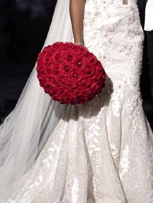 Bottom half of a bride in her dress holding our 13 inch red rose bridal bouquet.