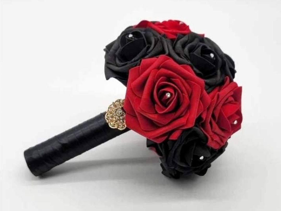 Red and black roses with satin black ribbon. Finished with a gold brooch. Rhinestones are on every rose. 