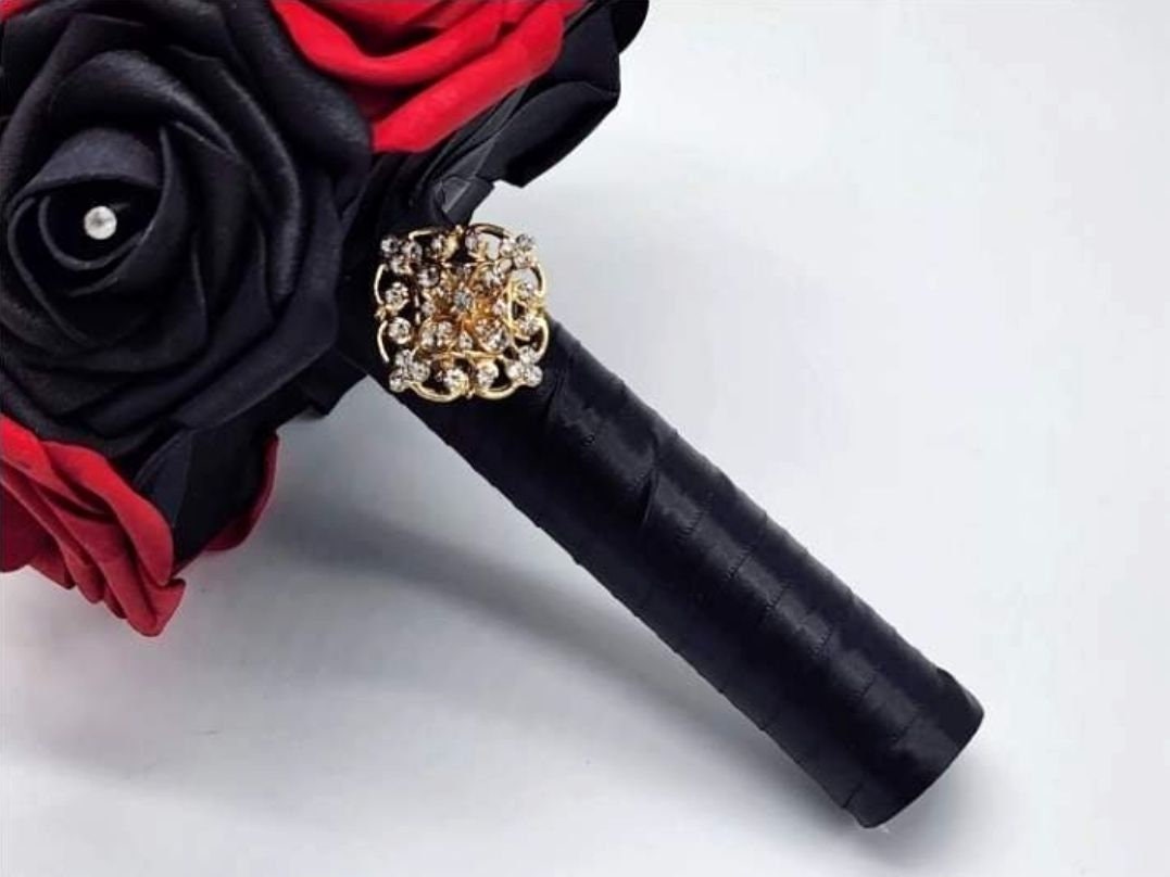 Black satin ribbon handle finished with a gold brooch.