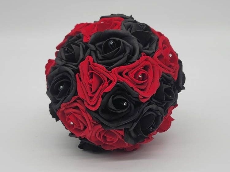 Front view of bouquet. Red and black roses with rhinestones in the center. 