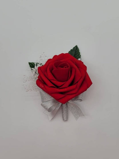 red boutonniere made with real touch roses and silver ribbon. Has baby's breath and a pearl pin