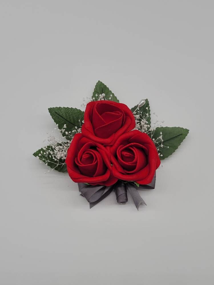 red corsage pin on with gray ribbon and babies breath. 