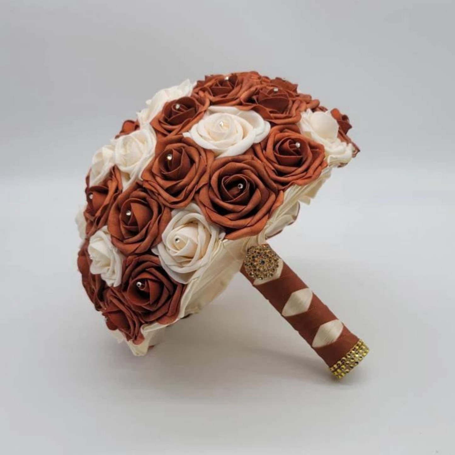 burnt orange and cream bridal bouquet with ivory and burnt orange french twist ribbon. Gold brooch and gold bling wrap on handle. 