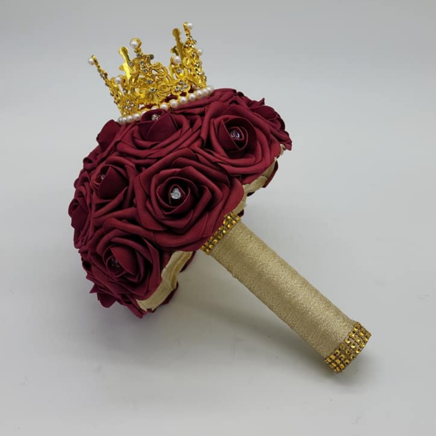 burgundy and gold bridal bouquet with gold crown and heart charms on flowers